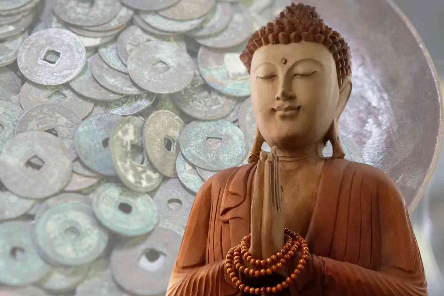 Staty av Buddha i förgrunden med gamla mynt i bakgrunden.