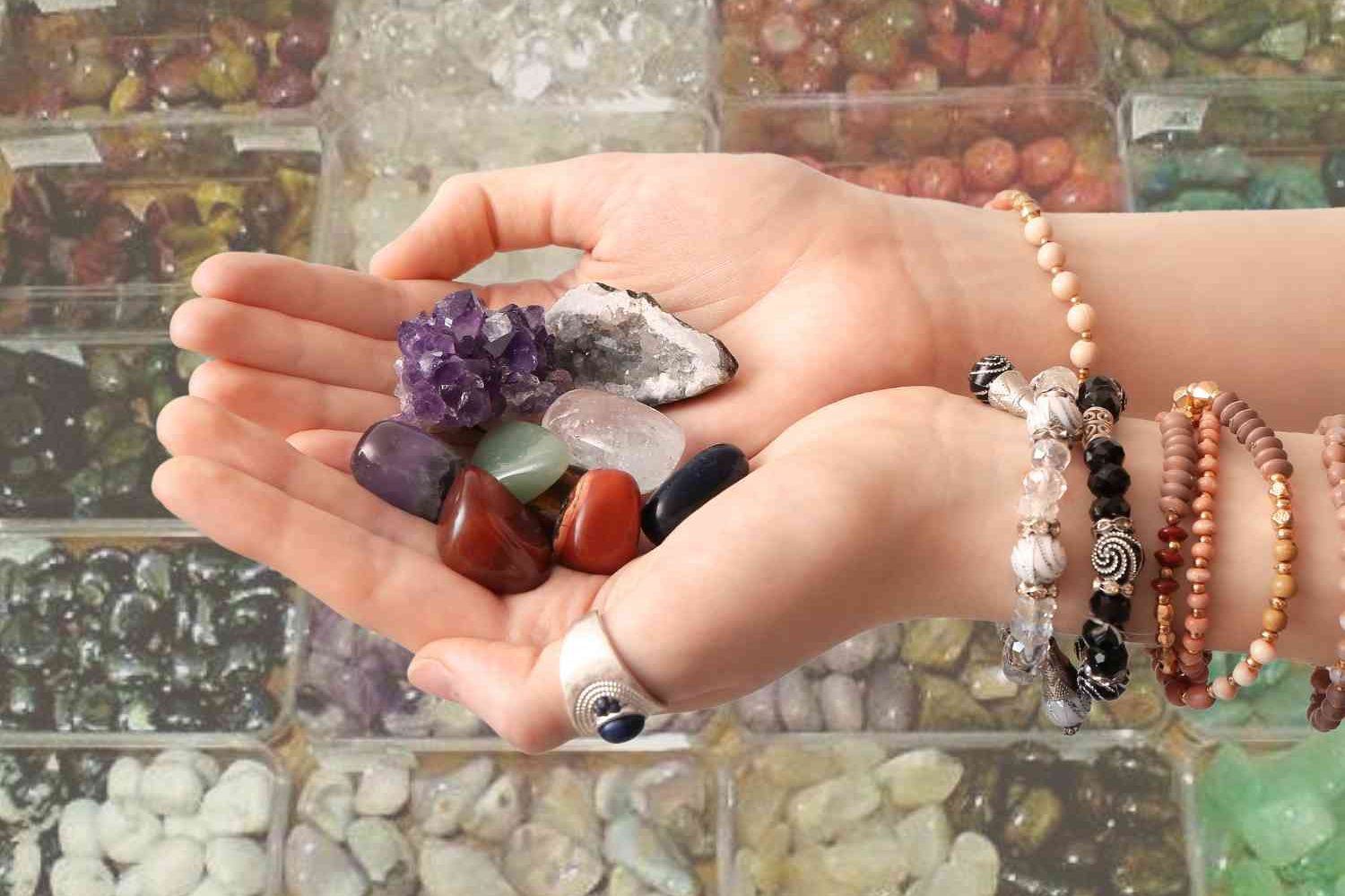 En hand håller ett urval av färgglada kristaller och stenar.